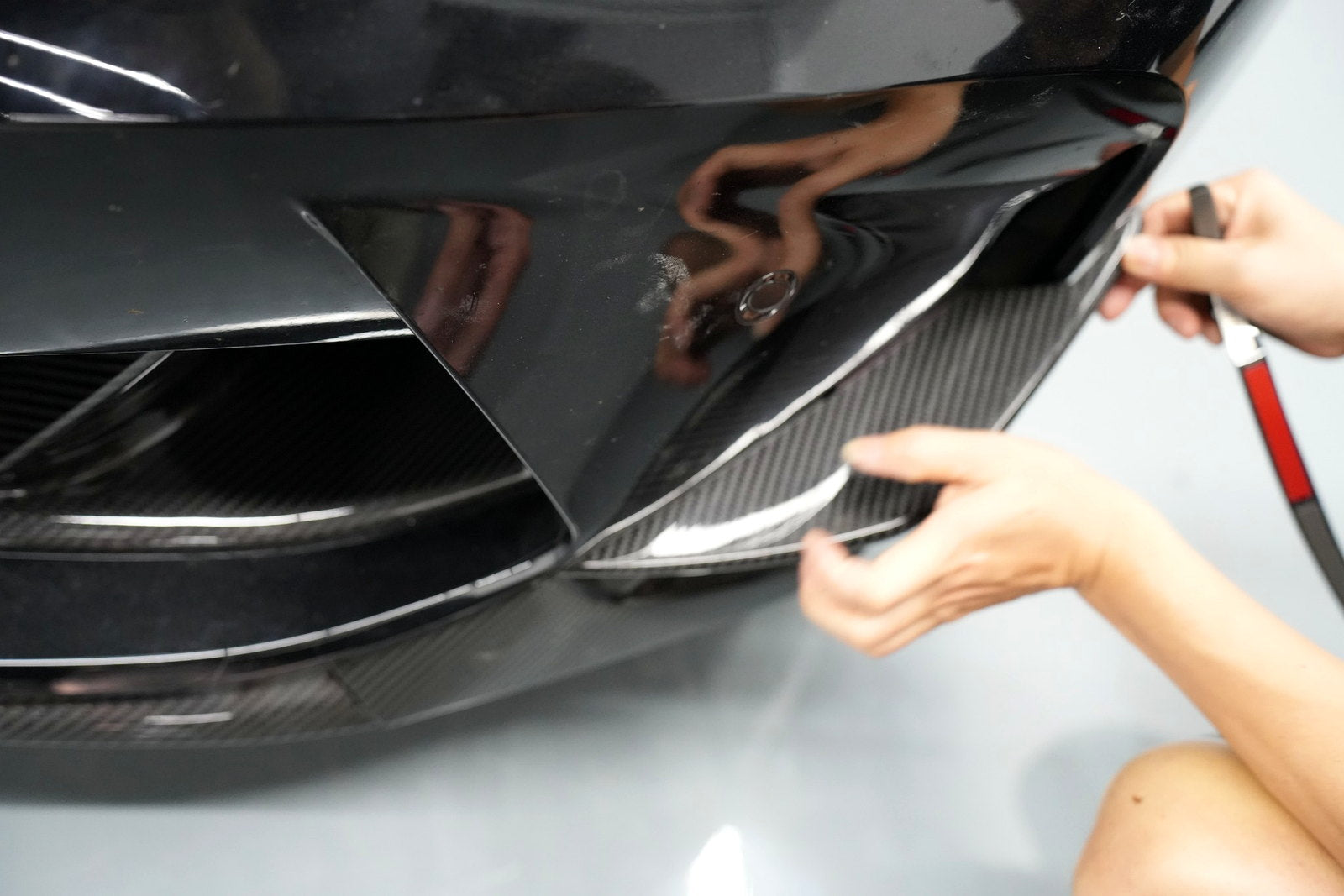 Installer aligning a carbon fiber front bumper fin on a BMW G80 M3