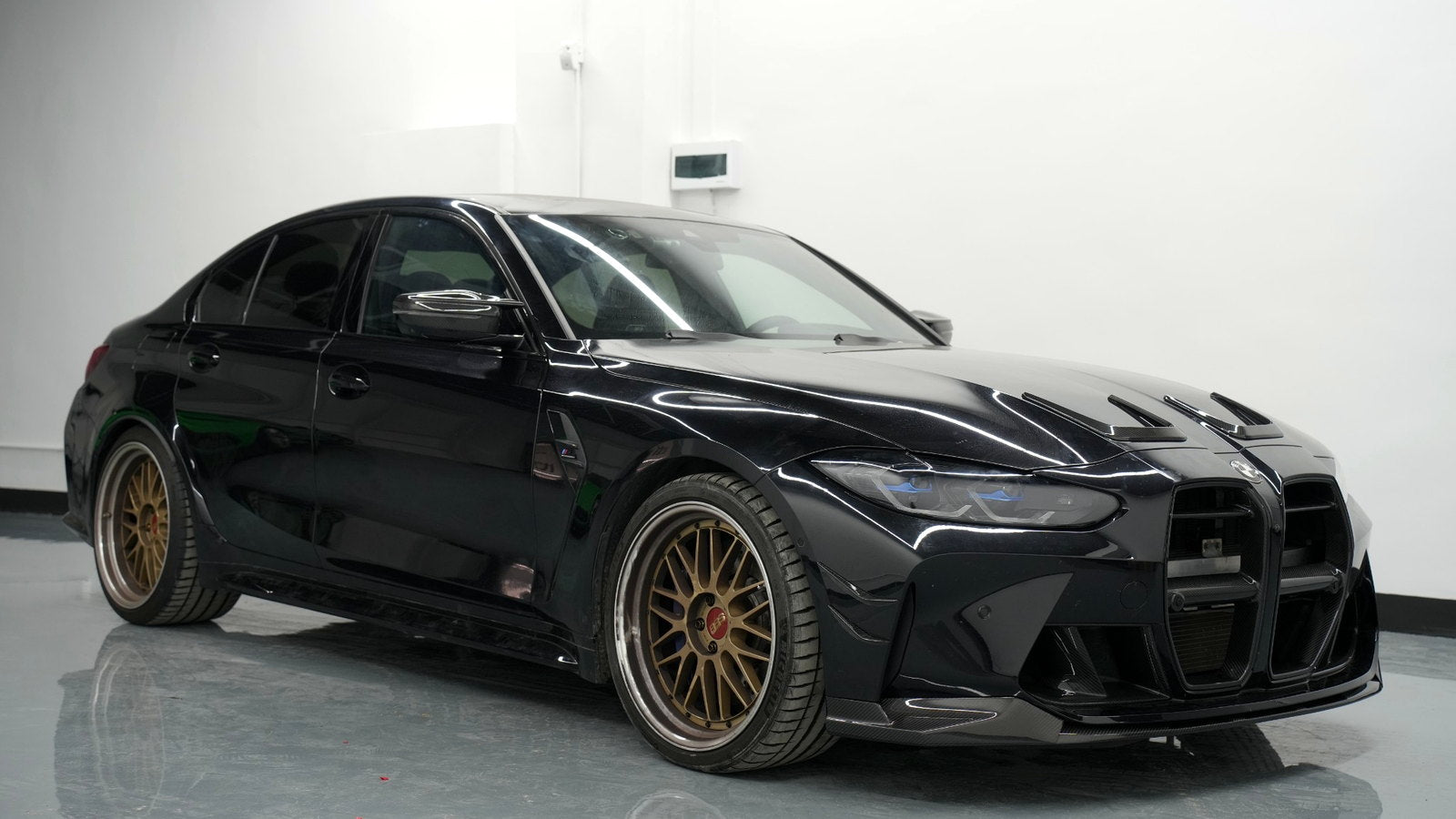 Black BMW G80 M3 with carbon fiber front lip, bumper fins and mirror caps