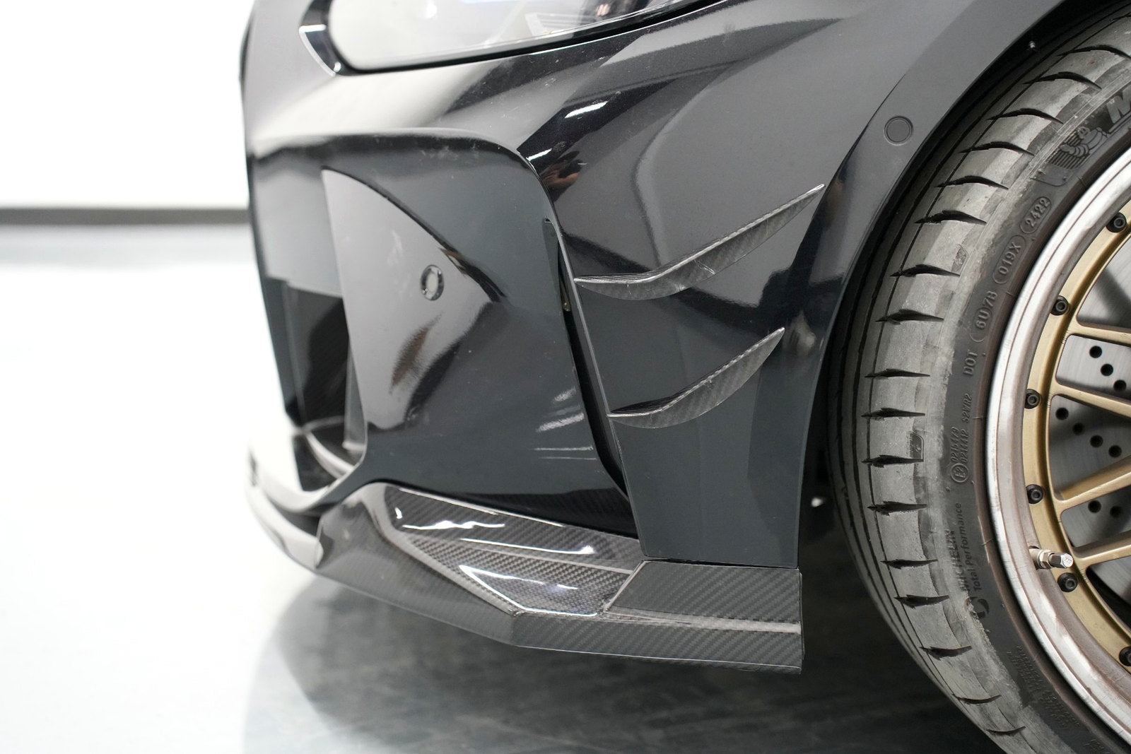 Close-up of BMW G80 M3 carbon fiber front lip and corner fitment