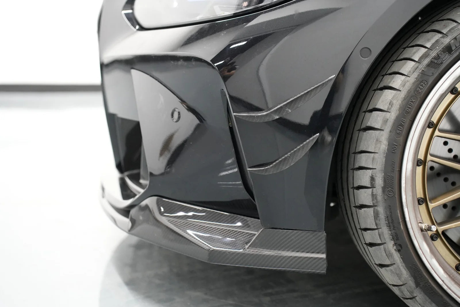 Carbon fiber front lip installed on a black BMW G80 M3
